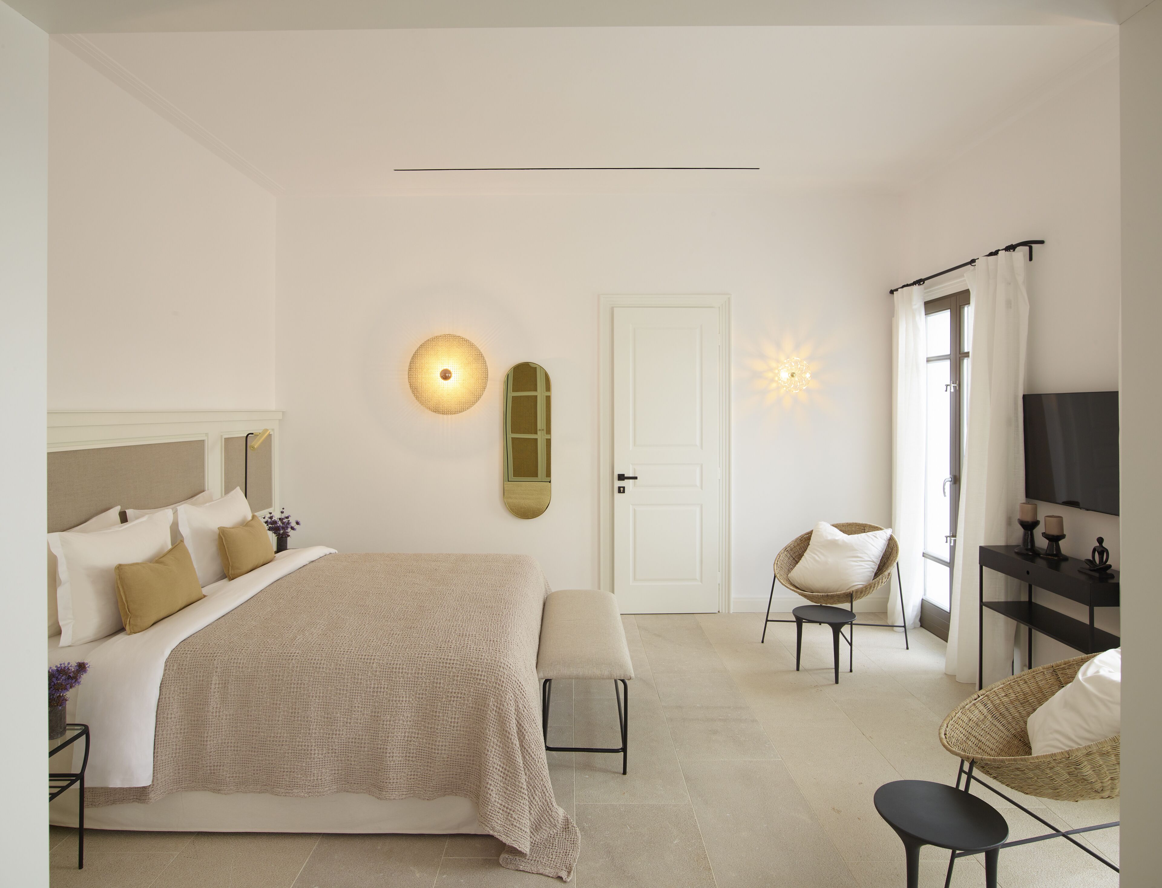 Un dormitorio moderno con una cama grande, mesitas de noche, una silla y un televisor.
