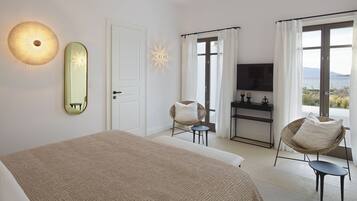Un dormitorio con cama, una silla, un televisor y vista al mar.