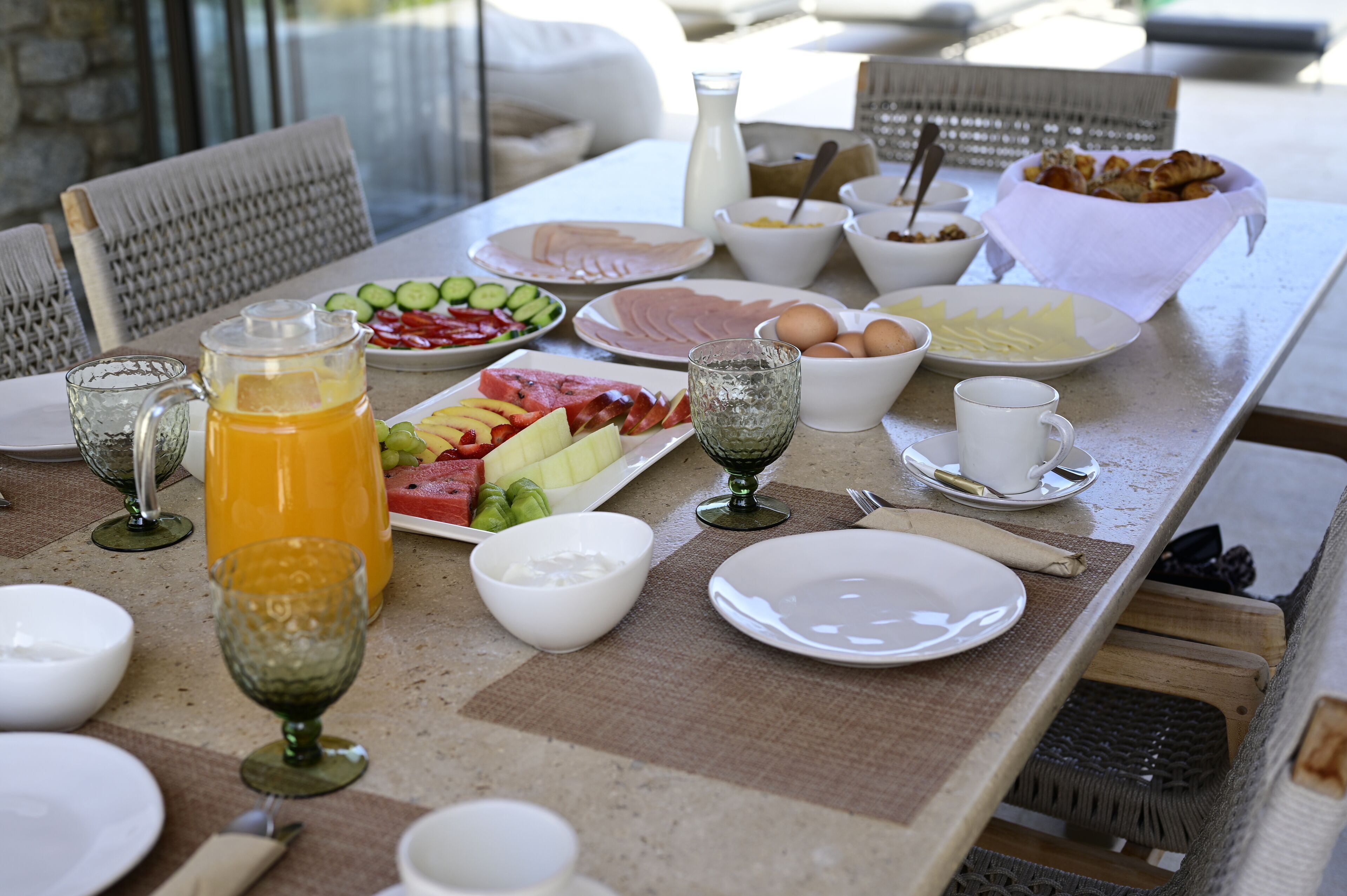 A breakfast table with various food items, including fruits, eggs, and pastries, along with drinks and bowls.