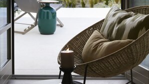 En balkon med en fletstol, et lille bord og et stearinlys.