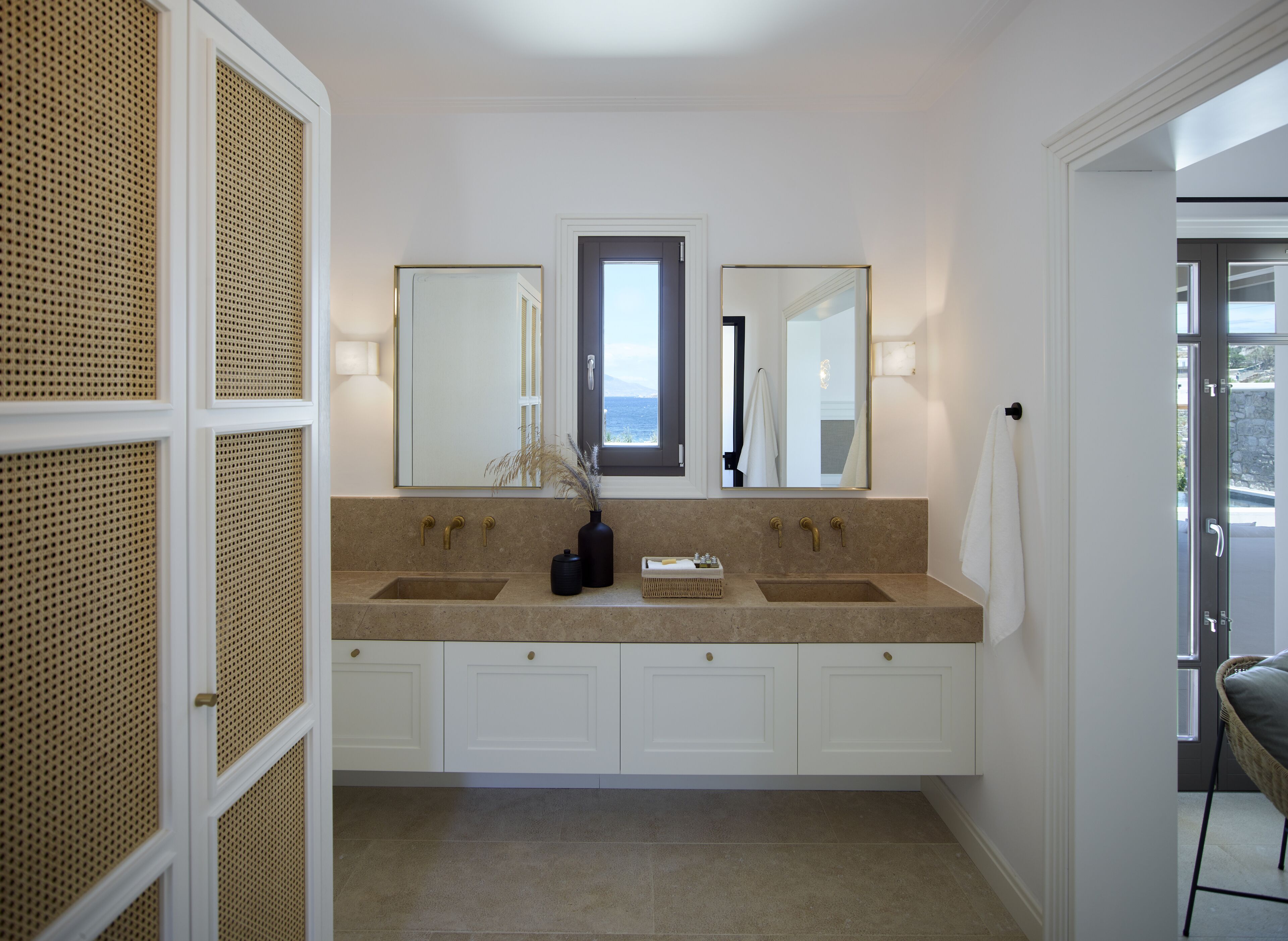 A bathroom with two sinks, a large mirror, and a window.