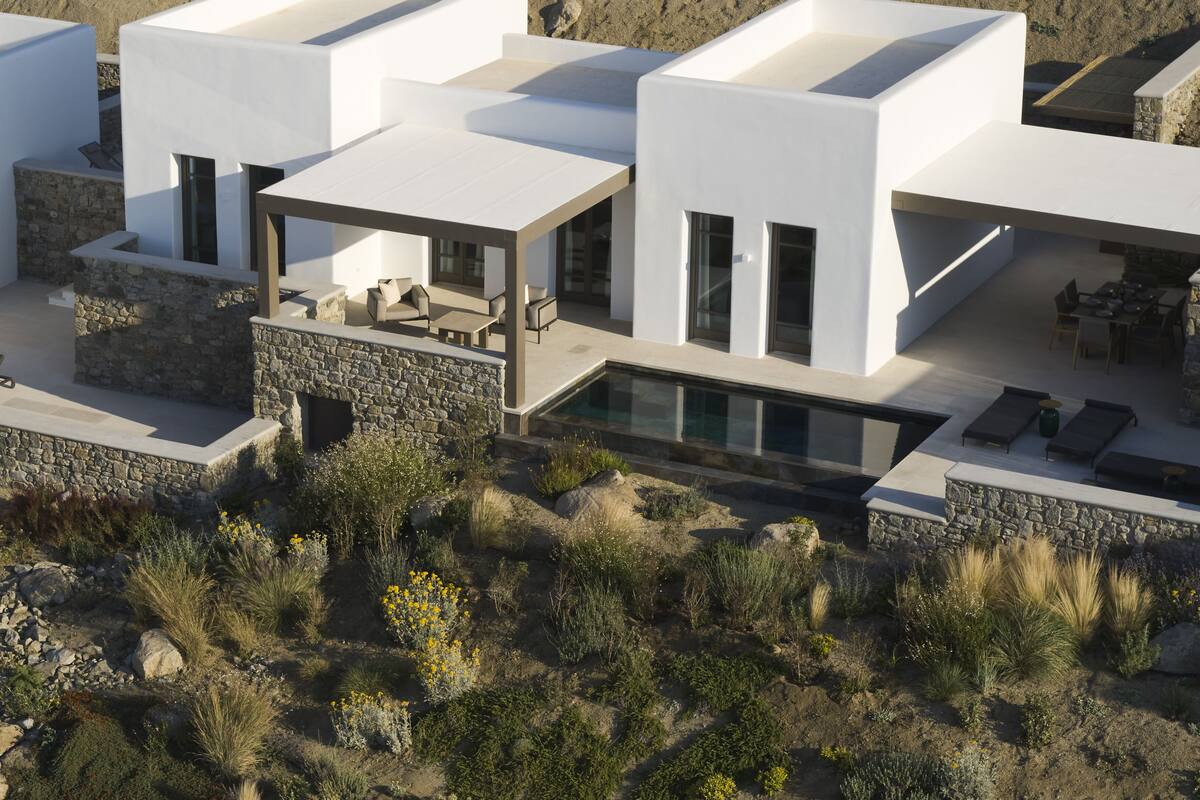 A modern multi-story building with a pool, outdoor seating, and a stone facade.