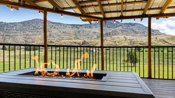 Ein Feuerkorb unter einer Pergola mit Blick auf eine Berglandschaft.