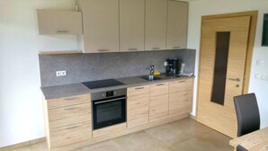 A modern kitchen with light wood cabinets, a black oven, a sink, and a coffee maker. - Agriturismo Gfaderhof Ferienwohnungen (Bressanone)