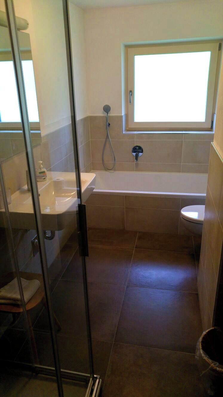A bathroom with a glass shower enclosure, a bathtub, and a toilet.