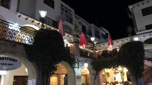 A restaurant with outdoor seating, arches, and string lights.
