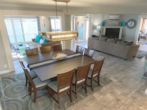 A dining area with a large table, chairs, and a hanging light fixture.
