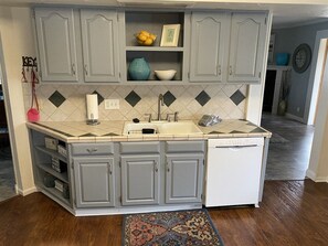 A kitchen with grey cabinets, a white dishwasher, and a tiled backsplash.