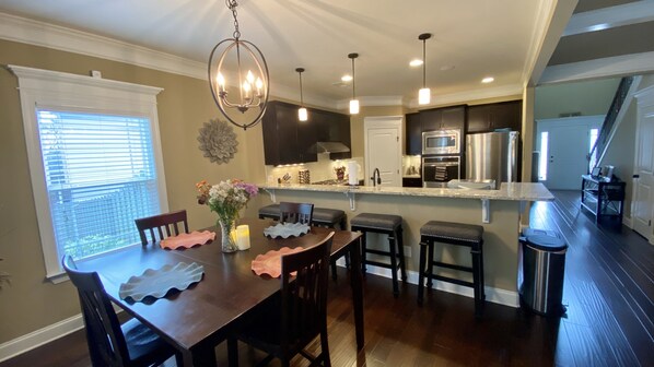 A modern kitchen with dark cabinets, stainless steel appliances, and a central island with bar stools.