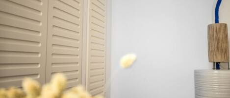 A room with a white wall, a beige door with a 'D' sign, a white cylindrical object, and a blurred foreground.