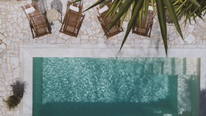 Una piscina al aire libre, sombrillas, sillones reclinables de piscina