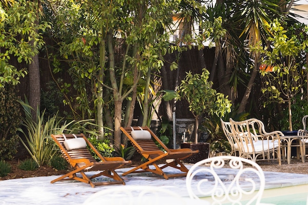 Una piscina al aire libre, sombrillas, sillones reclinables de piscina