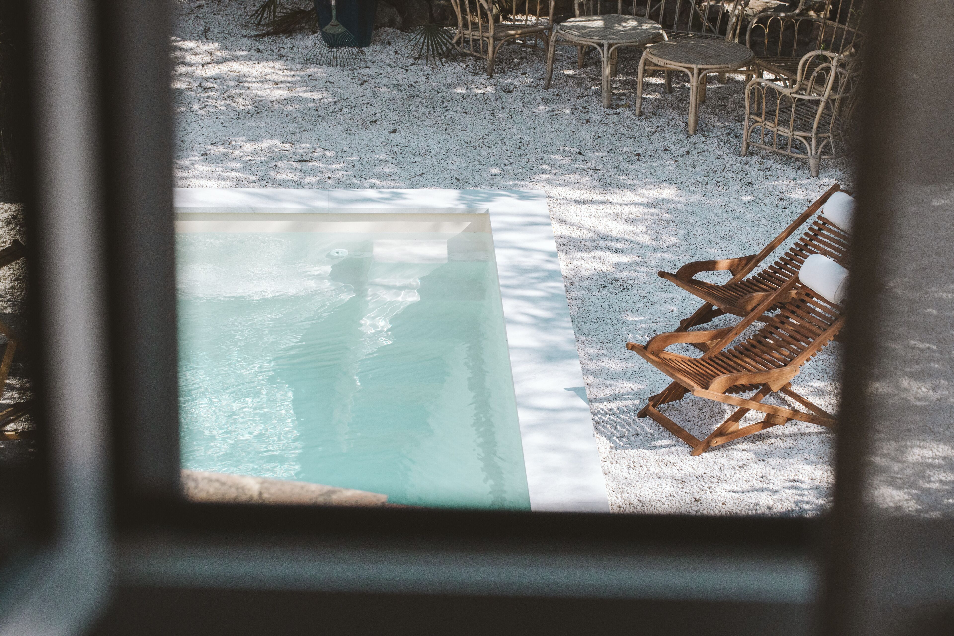 A poolside area with a wooden lounge chair and a table.