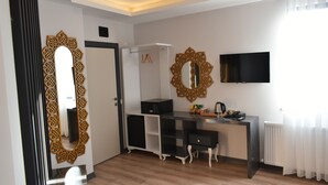 A modern room with a wooden floor, a black and white desk, a television mounted on the wall, and a decorative mirror. - Avcilar Garden Hotel (Istanbul)