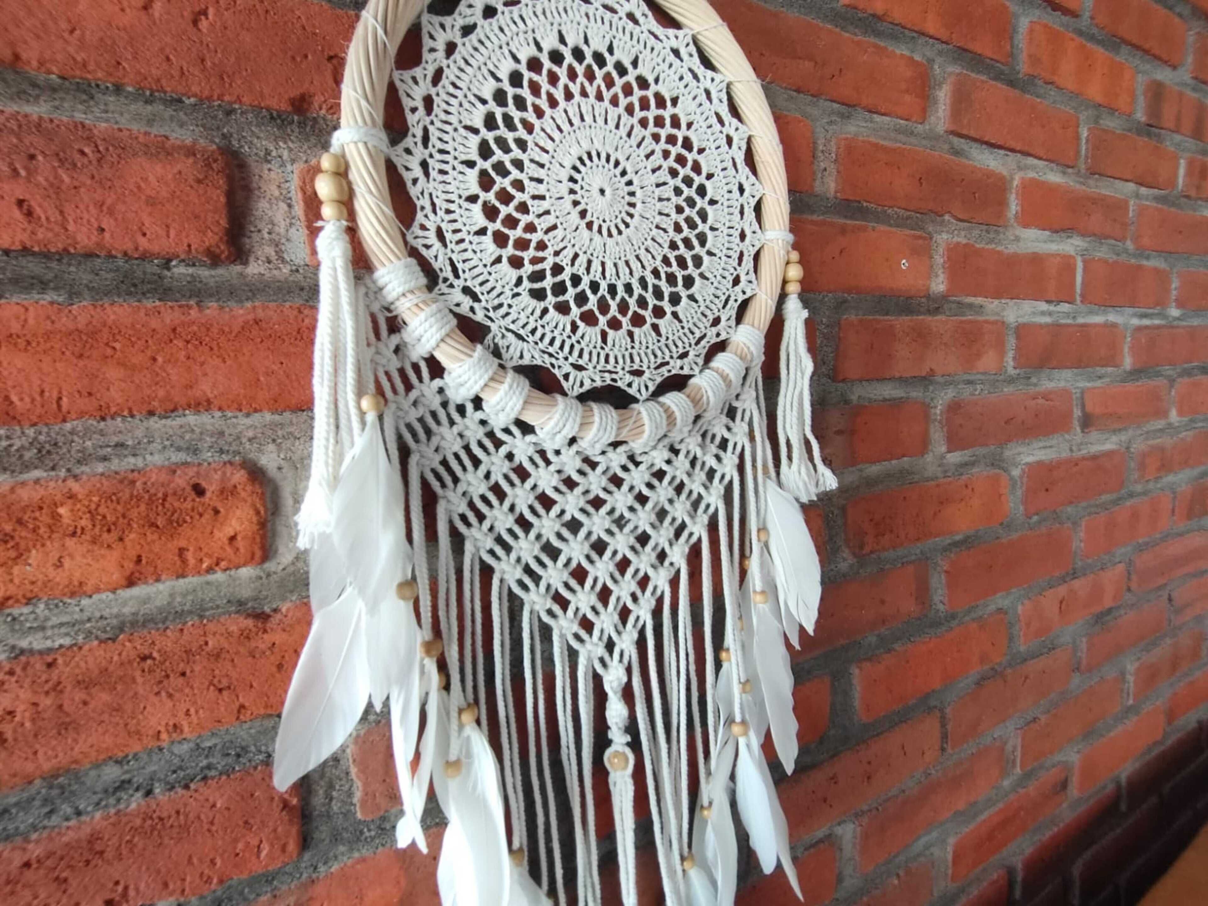 A macrame wall hanging with a circular center and fringes, hanging on a brick wall.