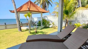 Un espace extérieur aménagé avec une zone de repos couverte, comprenant deux fauteuils de jardin en osier et un petit kiosque doté d’un toit en tuiles.