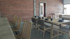 Un coin repas avec un mur en briques, des chaises en bois et une table dressée pour quatre personnes.