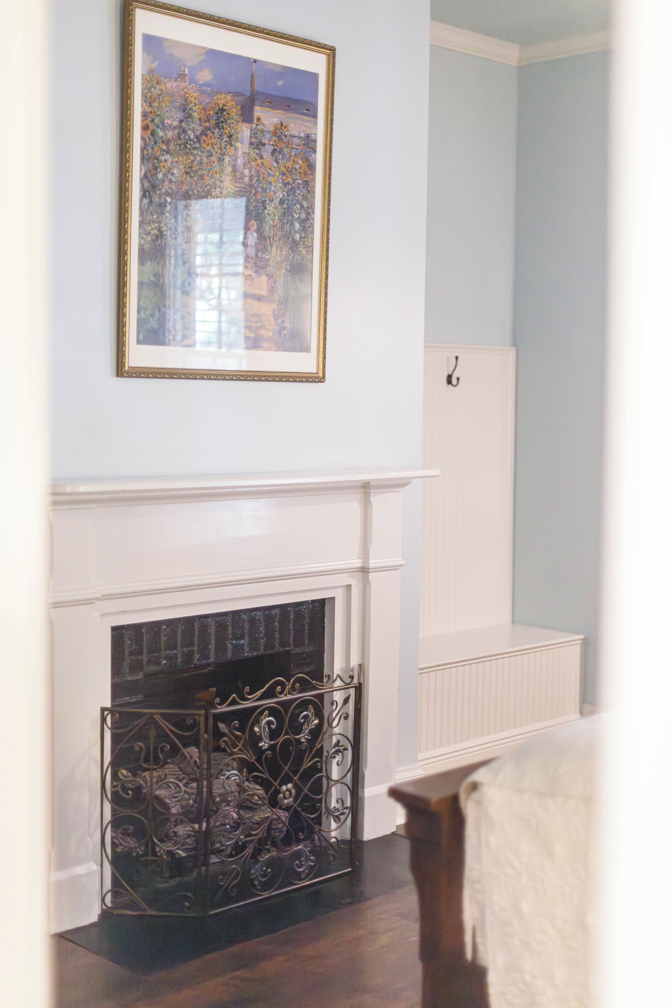A room with a white fireplace, a framed artwork above it, and a radiator on the wall.