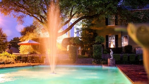 A swimming pool with a fountain, surrounded by trees and a brick pathway. - Anchuca Historic Mansion & Inn (Vicksburg)