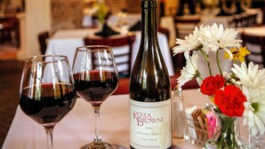 A table with a bottle of wine, two wine glasses, and a vase with flowers. - Anchuca Historic Mansion & Inn (Vicksburg)