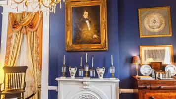 A room with a fireplace, a framed portrait, and a chandelier.