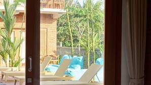 A hotel room with a bed, a view of a pool area, and a dining table with chairs. - Kubu Tropis (Ubud)