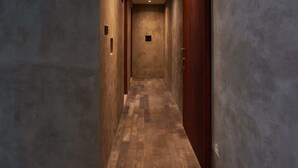 A hallway with a checkered floor, walls with a textured finish, and a wooden door on the right. - Kubu Tropis (Ubud)