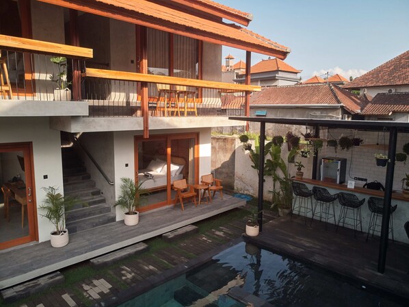 A multi-story building with a balcony, outdoor seating, and a small pool. - Kubu Tropis (Ubud)