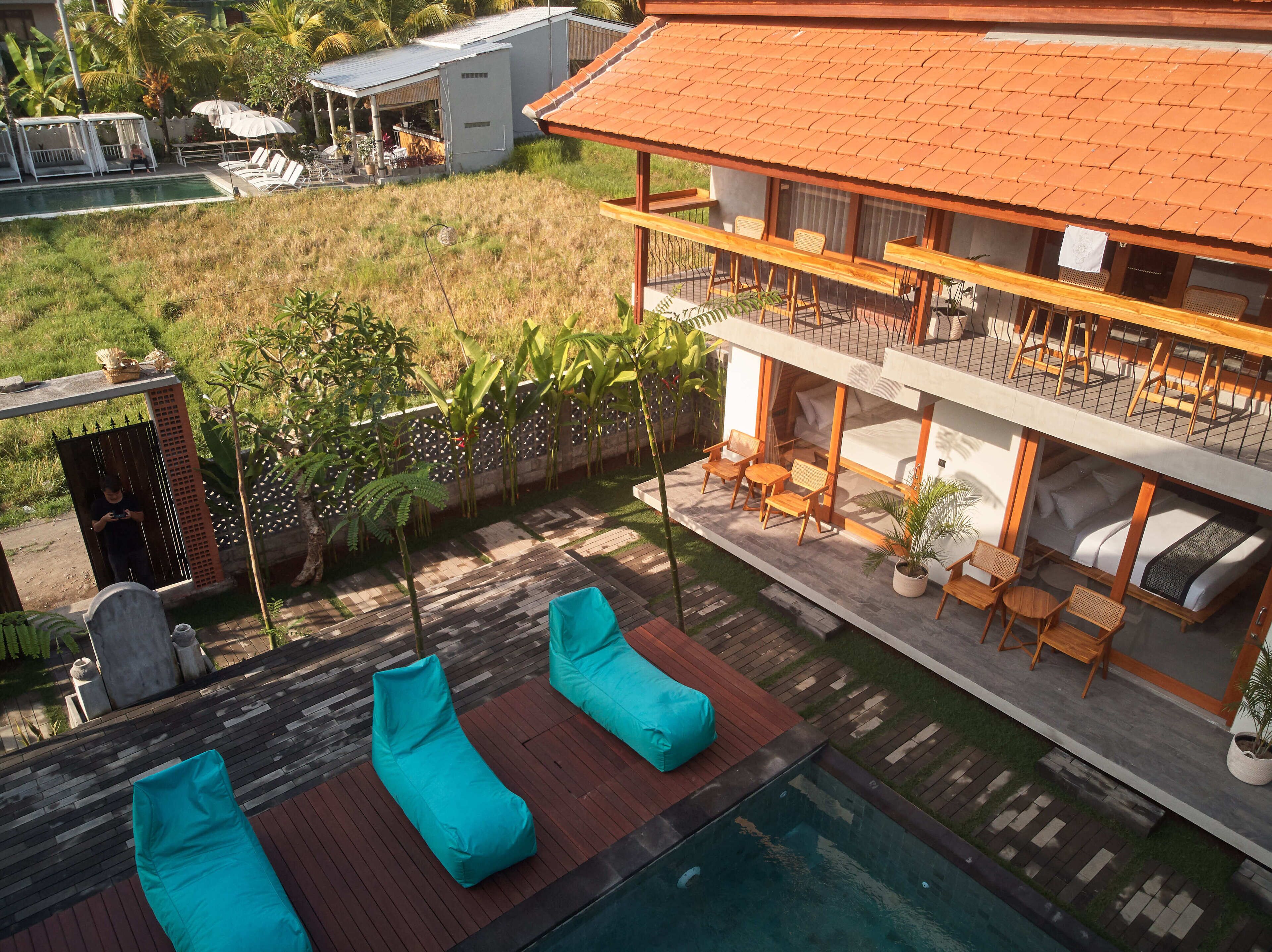 A modern two-story building with a rooftop terrace, a swimming pool, and outdoor seating.