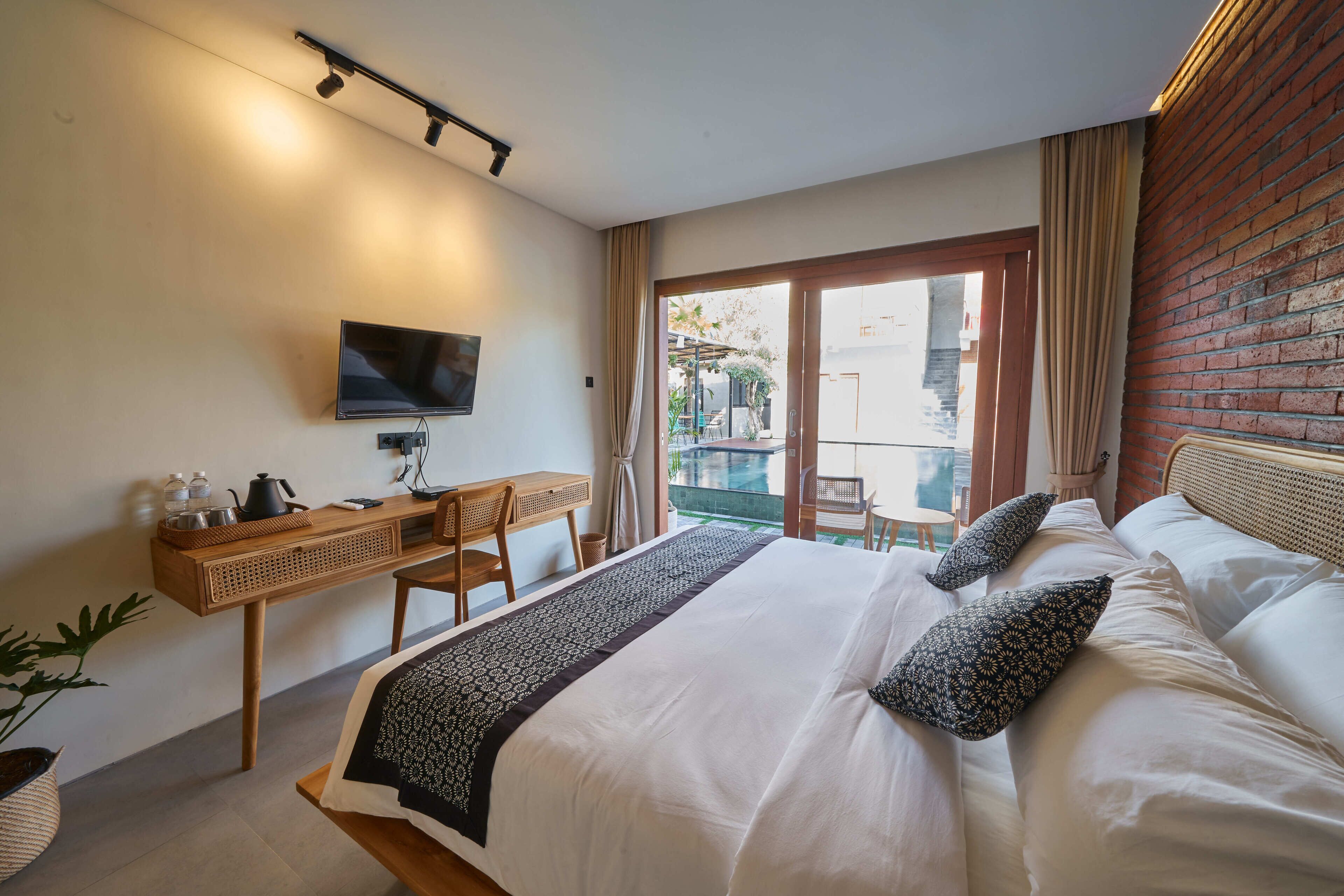 Una habitación de hotel con cama, escritorio, televisor y balcón con vistas.