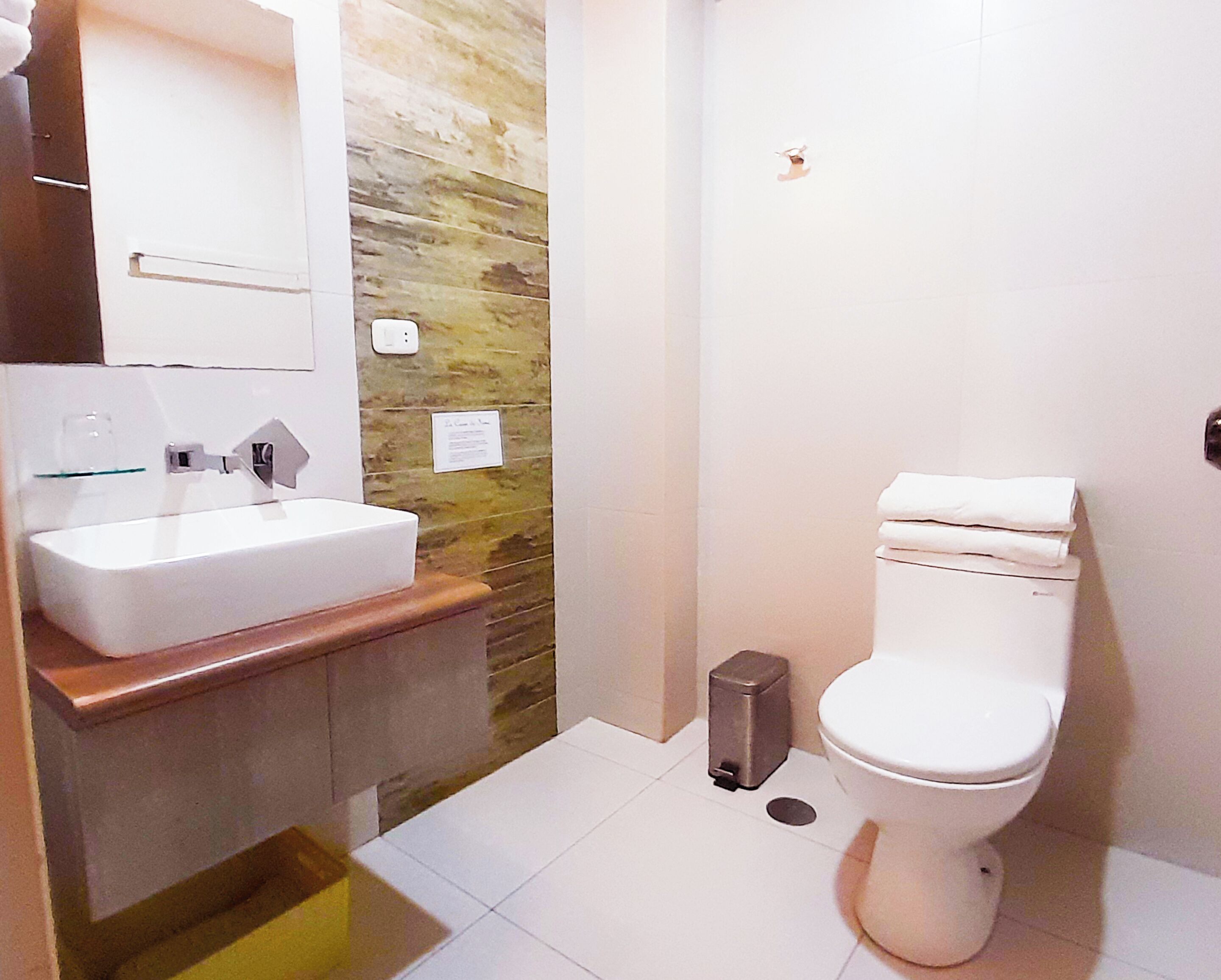 A bathroom with a white sink, a toilet, and a stone wall.