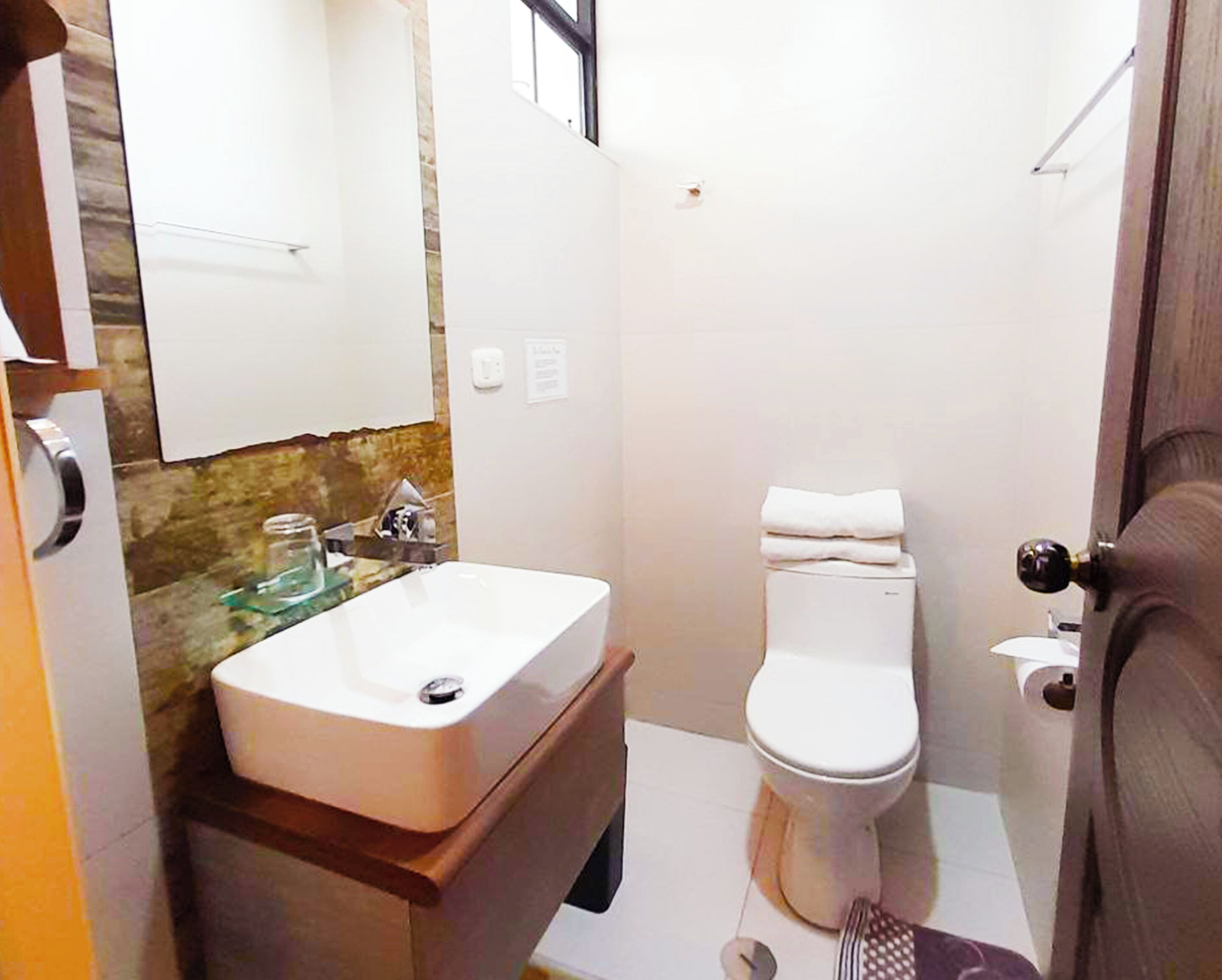 A small bathroom with a white sink, a toilet, and a mirror.