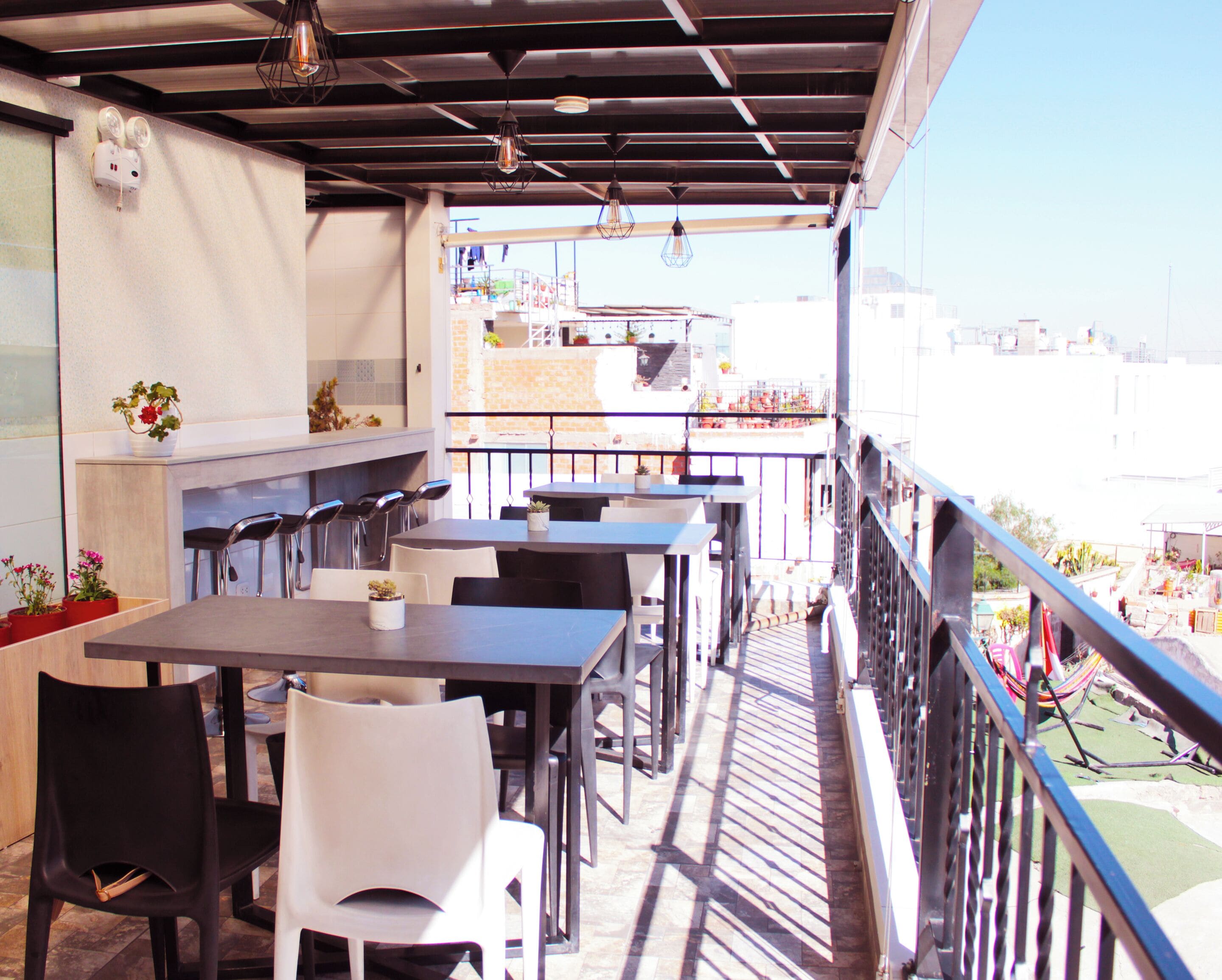 Un área de comedor al aire libre con mesas y sillas, barandilla y vistas panorámicas de la ciudad.
