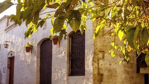 Una calle estrecha con un edificio blanco, puerta de madera y ventana con rejas de hierro.