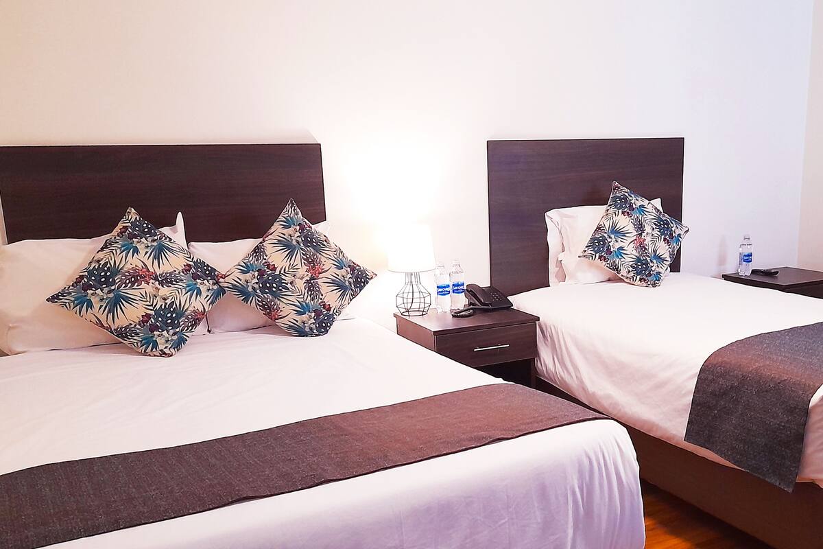 Dos camas con cabeceras a juego, sábanas blancas y almohadas estampadas con motivos florales.