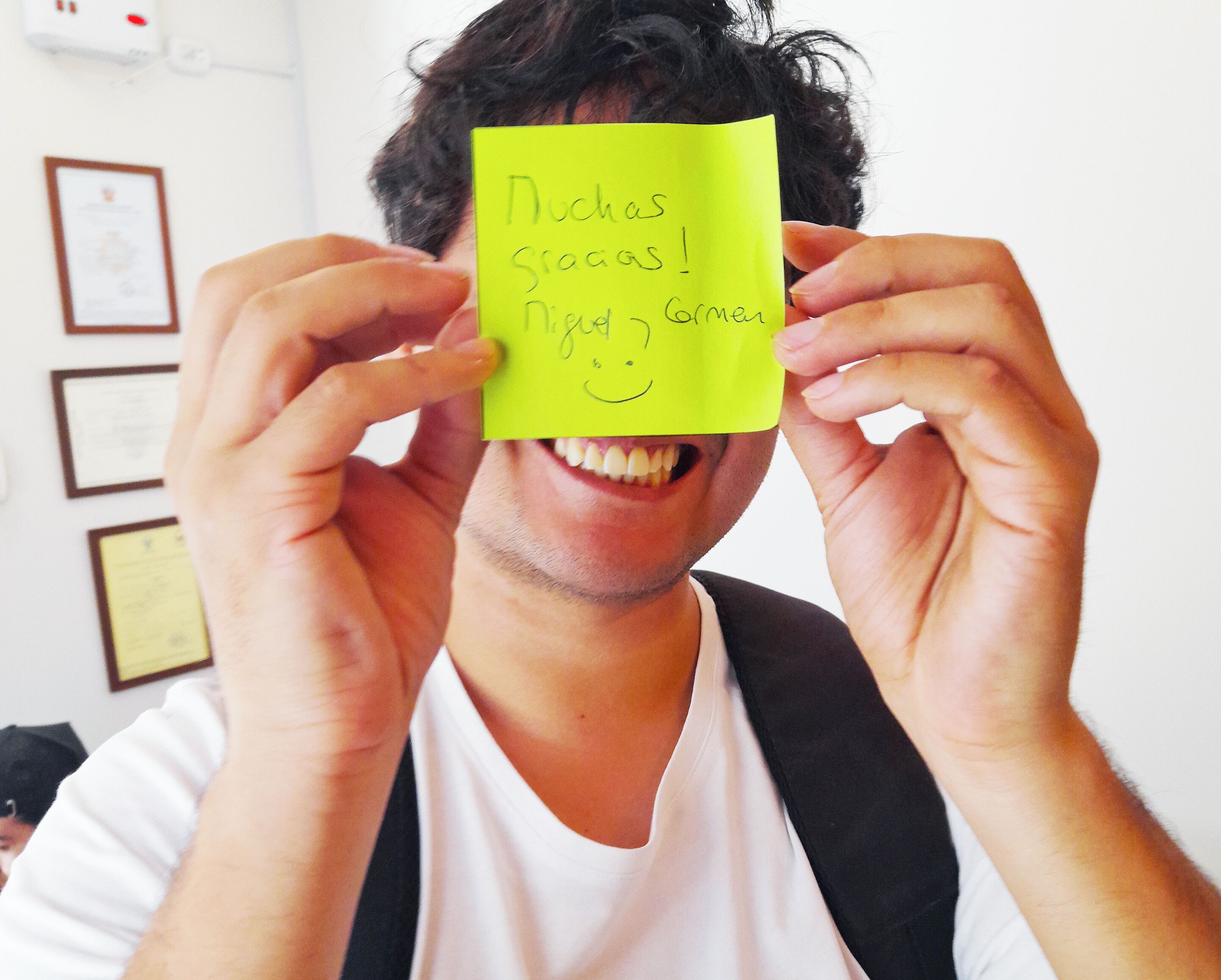 Una persona sosteniendo una nota adhesiva amarilla con texto frente a su rostro.