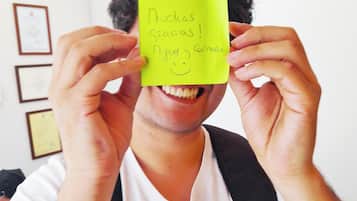 Una persona sosteniendo una nota adhesiva amarilla con texto frente a su rostro.