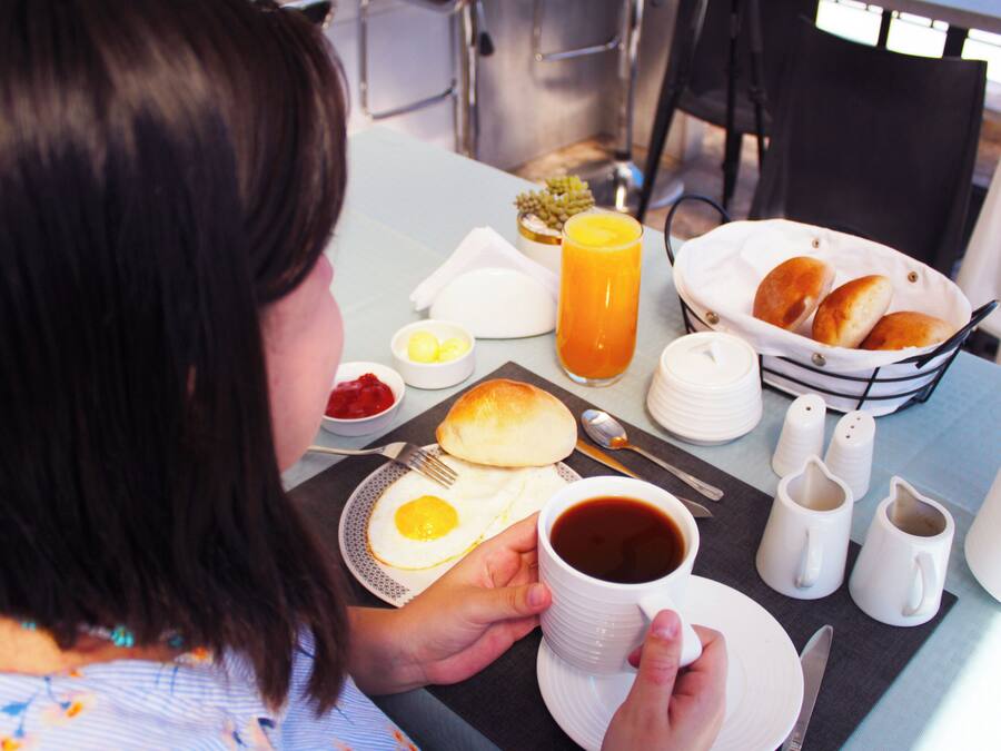 A breakfast setting with a plate of eggs, toast, and a cup of coffee.