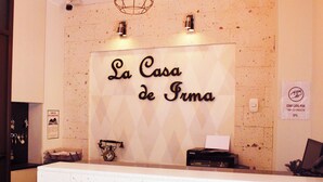 Una recepción con un cartel que dice "La Casa de Fuma". Hay un teléfono antiguo e impresora sobre el mostrador.