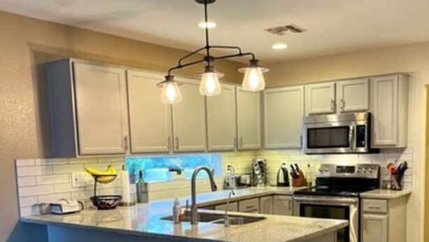 A kitchen with a central island, bar stools, a microwave, and a stove. - Beautiful 2 BR Plus Loft, Attached 2 Car Garage, Recently Updated! (Scottsdale)