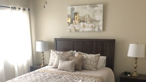 A bedroom with a large bed, two bedside tables with lamps, a ceiling fan, and a wall-mounted abstract painting. - Beautiful 2 BR Plus Loft, Attached 2 Car Garage, Recently Updated! (Scottsdale)