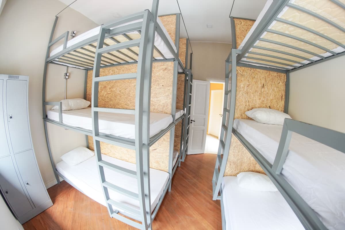 A bunk bed room with a wooden floor, a wardrobe, and a door.