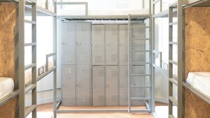 A dormitory room with bunk beds, a wooden floor, and a row of lockers in the center. - Quintal Hostel (São Paulo)