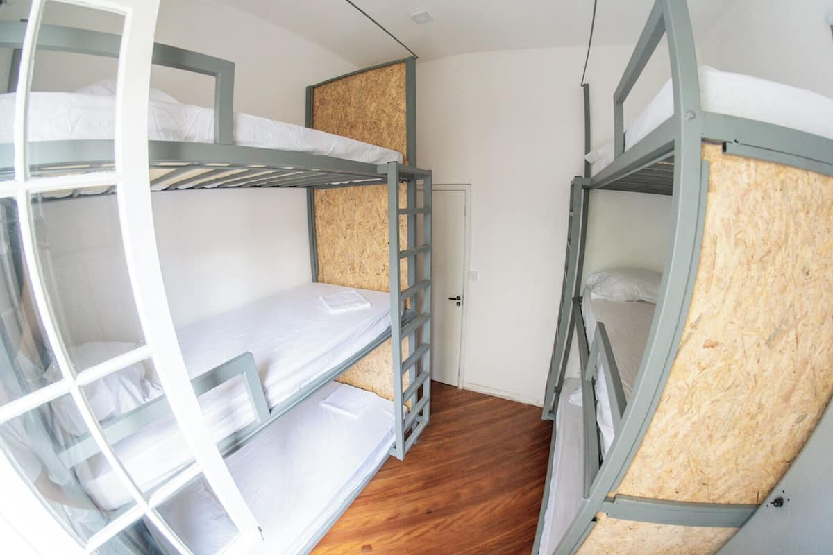 A compact room with bunk beds, wooden flooring, and a door.