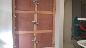 Ein Zimmer mit einem großen Holfachschrank, einem türkisfarbenen Ventilator und einem weißen Tisch.