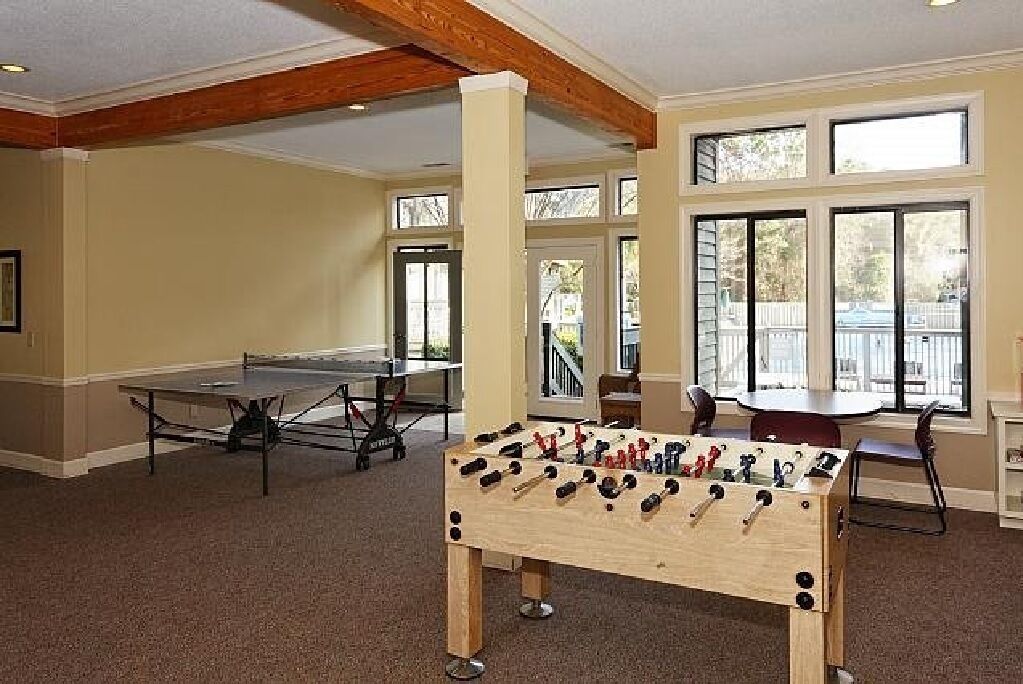 A room with a foosball table, a ping pong table, and a billiards table.