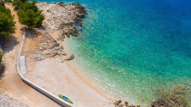A coastal beach with clear turquoise waters, rocky shoreline, and a narrow path leading to the beach. - Sun Dance Luxury Villa II (Primošten)