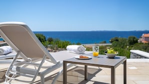 A sun lounger and a table with a plate of food, a glass of orange juice, and a bowl of grapes, overlooking a clear blue sea. - Sun Dance Luxury Villa II (Primošten)