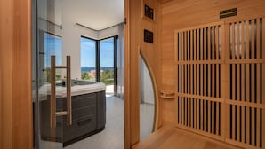 A modern bathroom with a glass shower enclosure, a wooden sauna door, and a visible hot tub. - Sun Dance Luxury Villa II (Primošten)