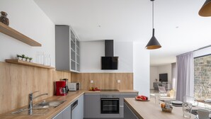Eine moderne Küche mit Holzarbeitsplatte, Edelstahlspüle und integriertem Backofen. Auf der Arbeitsfläche steht ein roter Wasserkocher und ein Glasbehälter.